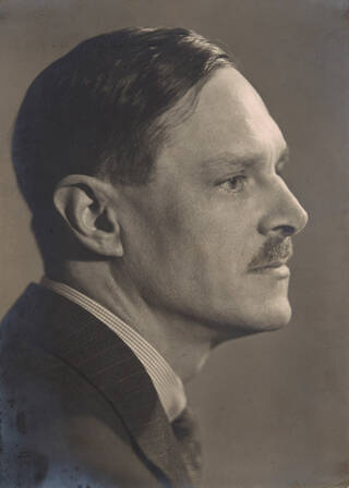 Black and white photograph of head and shoulders of man with head turned to the side